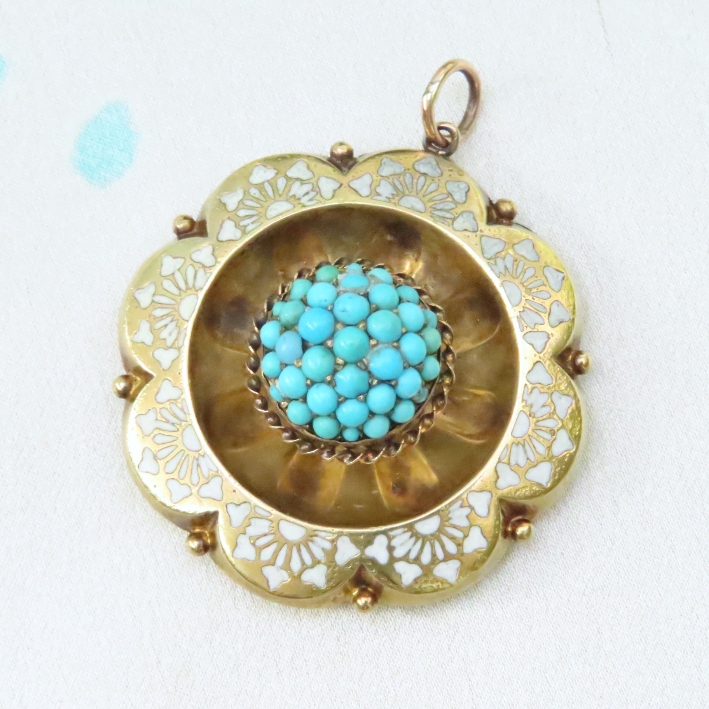 turquoise cabochon dome pendant with white enamel detail with a scalloped gold border in 12ct gold. Victorian dating to 1870.